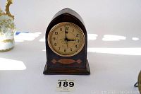 Front view of vintage Telechron wooden mantel clock with beige dial and black Arabic numerals, no glass front.