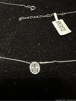 Close-up of silver Charmed Aroma necklace with oval cubic zirconia pendant on black background