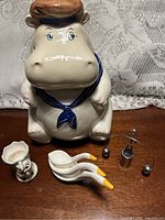 Group shot of hippo cookie jar, goose spoons, chick egg cup, metal balancing man
