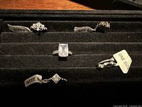 Five rings displayed in jewelry tray showing size tags