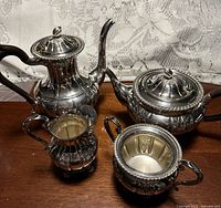 Full view of all four silver-plated pieces on wooden surface