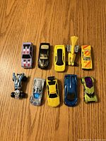 Overhead image of ten 1:64 scale die-cast toy cars on wood surface