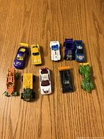 Group shot of ten assorted die-cast toy cars arranged on wooden surface