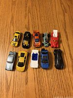 All ten die-cast toy cars on wood surface