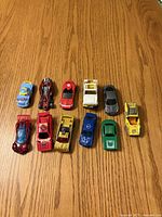 Top view of eleven assorted toy cars on wood surface