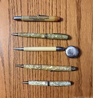 All five writing instruments laid out on wood surface