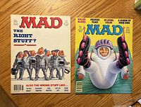 Front covers of both MAD magazines on wooden surface