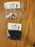 Two sealed packs of bucktail jigs, white and black, with The Fishing Tackle Guy headers