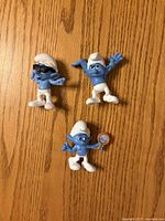 Front view of three Smurf figurines on wood surface