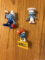 Front view of three Smurf figurines displaying characters and accessories