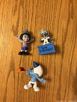 Front view of three Smurf figurines on wood surface