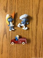 All three Smurf toys on wood surface
