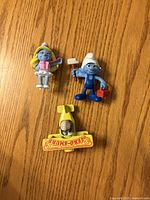 Front view of three Smurf items on wood surface