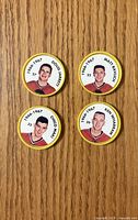 Front view of four 1966-67 Chicago Black Hawks player coins on wood surface