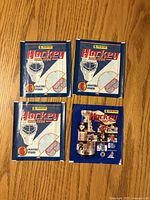 Front view of four sealed Panini hockey sticker packs