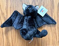 Front view of black plush bat showing wings, face, and hangtag