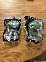 Front view of both sealed Disney Pixar Happy Meal toys showing Buzz Lightyear and Mike Wazowski figures inside original bags