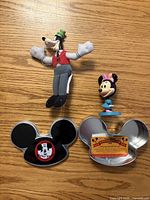 Group view Goofy plush, Minnie figure, Mickey head tin lid and base
