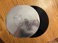 Front of round silver-foil jacket with partial view of vinyl