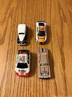 All four diecast toy cars displayed on wooden surface