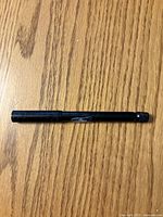 Full view of capped black fountain pen on wood surface