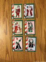 Fronts of six Santa Around the World trading cards laid out on wood surface
