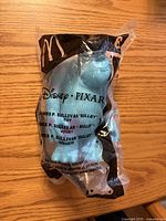Front view of sealed Sulley Happy Meal toy in clear bag showing Disney·Pixar branding