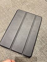Closed black tri-fold case covering iPad