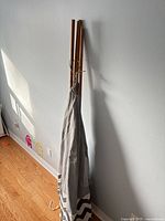 Folded grey canvas teepee with bamboo poles leaned against wall