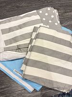 Stack showing grey & white striped textiles, polka-dot rail protector, white mattress cover, blue pad edge