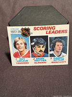 Front of O-Pee-Chee #65 card showing portraits of Guy Lafleur, Bryan Trottier, Darryl Sittler