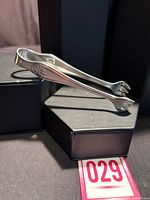 Full view of silver-plated sugar tongs on display box