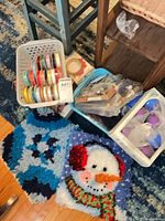 Assorted ribbon spools in basket, hooked rug panels, ornament box