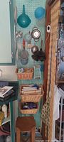 overview of pegboard with baskets, colanders, duster, stool