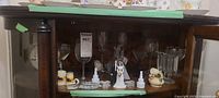 Full shelf showing glassware, cruet, figurines, candle holders