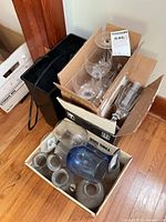 Boxes containing various glassware pieces and small black paper shredder