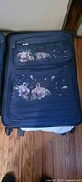Front view of larger suitcase showing floral design and front pockets