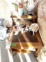 Front view of one end table showing leather inset top, stepped design, figurines on surface (not included)
