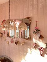 Wide shot showing wall with corbel, fabric knot and multiple small resin hangings (mirror excluded)