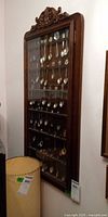Full view of wall-mounted wooden spoon cabinet with glass door