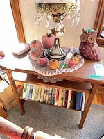 Front view of wood side table showing top surface, lower shelf with books, finishing details