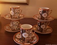 Five patterned demitasse cups each on its saucer, showing design and gilt accents