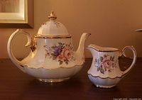 Teapot and creamer front view showing floral pattern and gold trim