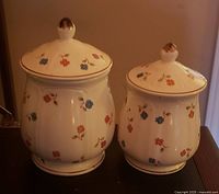 Two cream floral porcelain canisters with lids