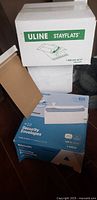 Stacked Uline StayFlat boxes and Aimoh security envelopes box