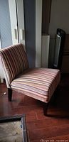 Side view of striped armless accent chair showing upholstery and legs
