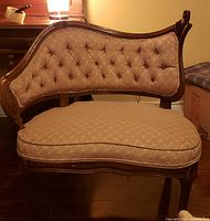 Front view of carved wood lounge chair showing tufted backrest and seat cushion