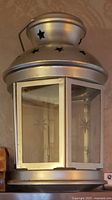 Front view of silver metal lantern showing star cutouts and glass panes