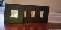 Four black square mirror frames leaning against wall