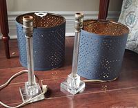 Two acrylic lamp bases and two blue drum shades displayed on floor